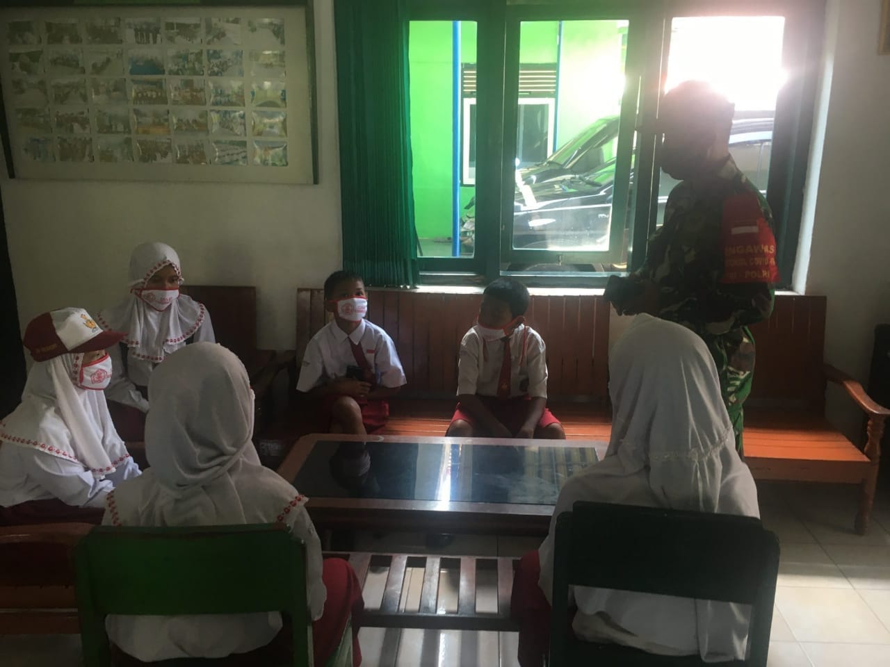 BELAJAR DARING: Sertu Nursalim bersama siswa-siswi Sekolah Dasar yang tengah belajar dengan memanfaatkan wifi di Makoramil Sumberpucung.