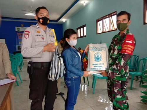 DAMPINGI: Babinsa Karangploso bersama Bhabinkamtibmas menyalurakan bantuan BST kepada warga.