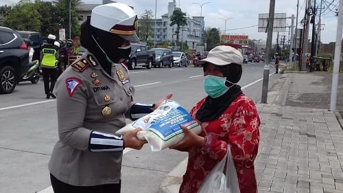 SEMBAKO: Kasat Lantas Polres Malang AKP Diyana saat memberikan bantuan sembako kepada masyarakat.