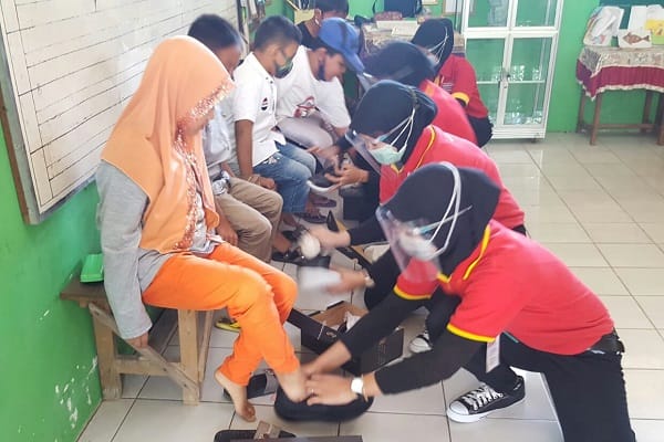 SEPATU BARU: Karyawan Alfamart saat memakaikan sepatu baru kepada siswa SD hasil dari donasi konsumen Alfamart.