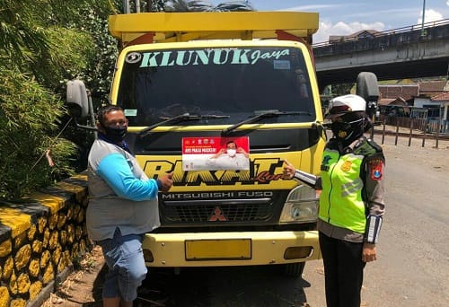 TRUK:Briptu Mirza Yunita saat memasang stiker Imbauan Ayo Pakai Masker di mobil truk.
