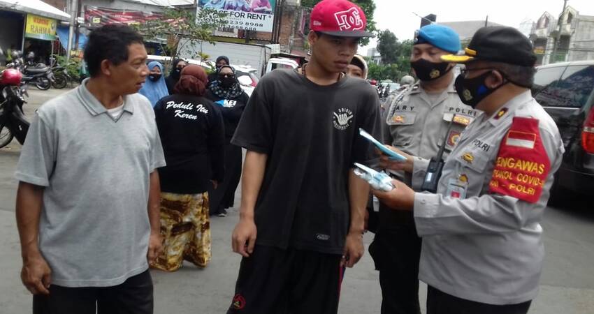 BAGIKAN: Kapolsek Sukun Kompol Suyoto saat memberikan masker kepada masyarakat yang tidak memakai masker.