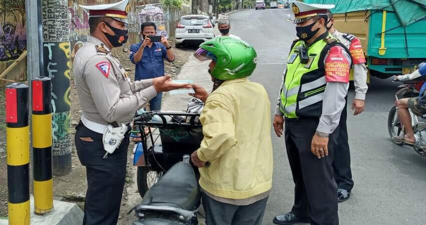 MASKER: Kanit Dikyasa Polres Batu Ipda Huda saat membagikan masker kepada masyarakat pengendara.