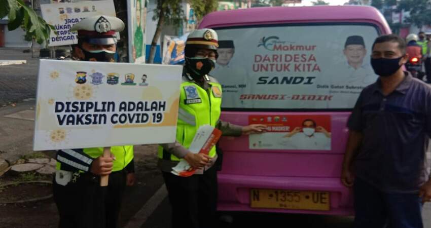 STIKER: Anggota Satlantas Polres Malang saat memasangkan stiker imbauan Ayo Pakai Masker di angkutan umum.